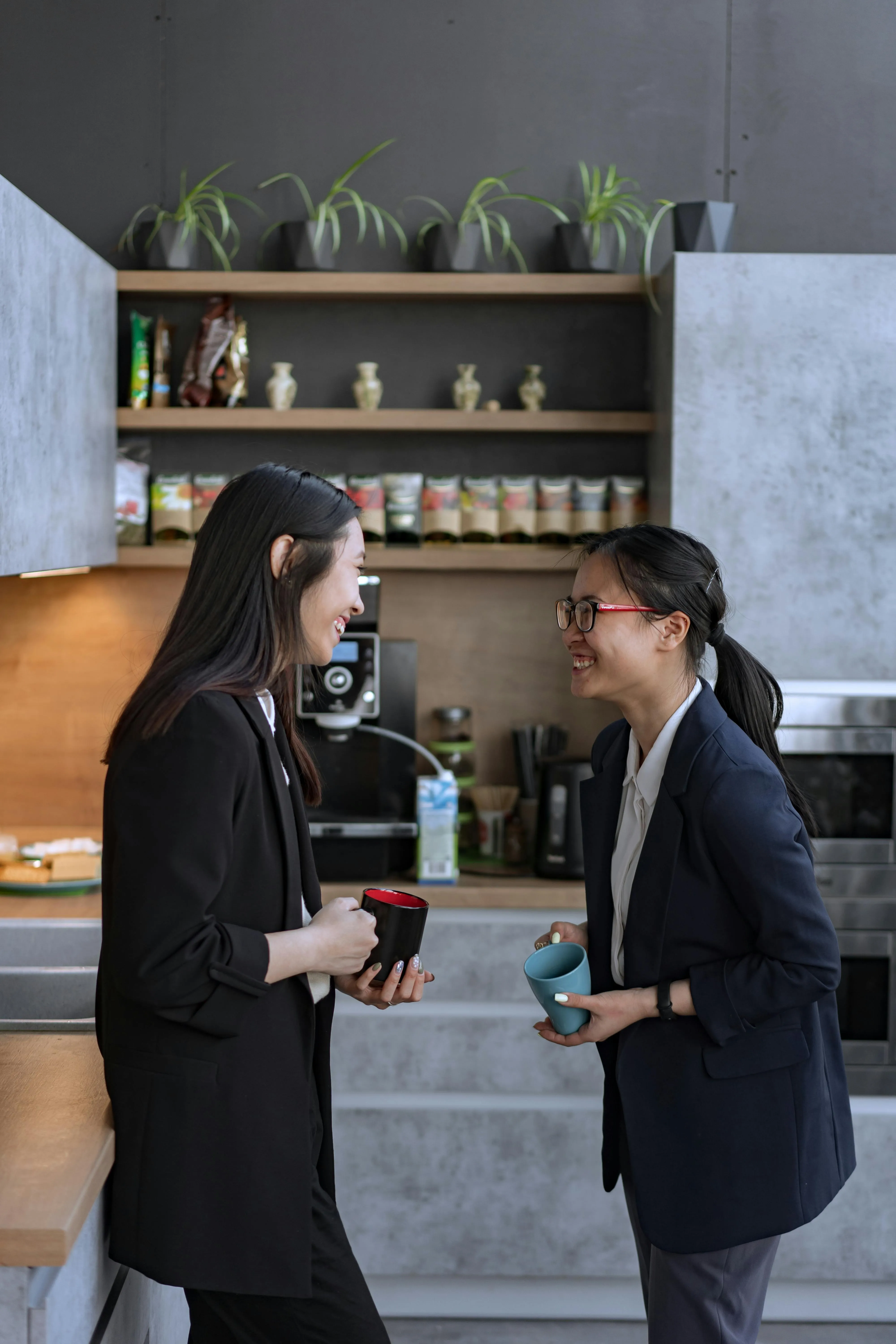 Two men stand with their lattes in front of the coffee machine in the office. Their happy appearance conveys an image of joy and satisfaction. This shows how friendship among colleagues can have a positive impact on the work atmosphere.